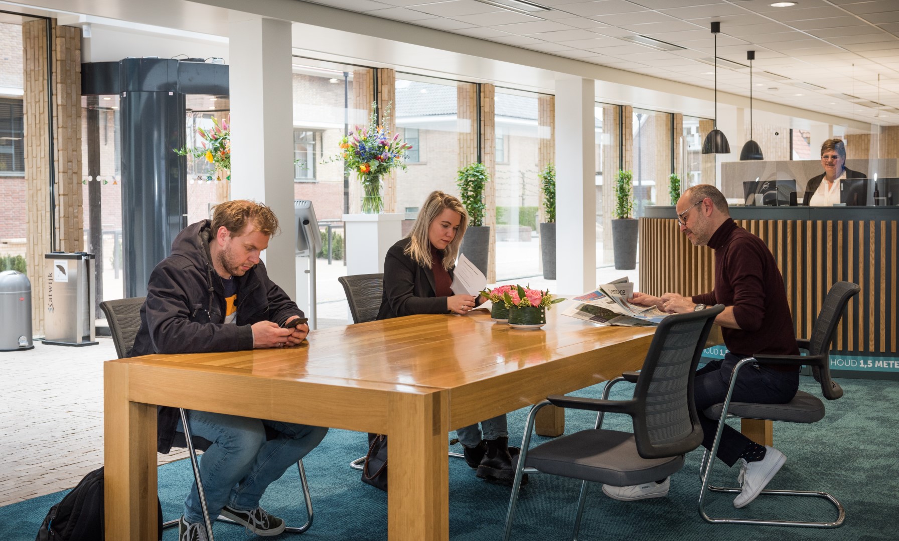 Bezoekers aan tafel in wachtruimte gemeentehuis